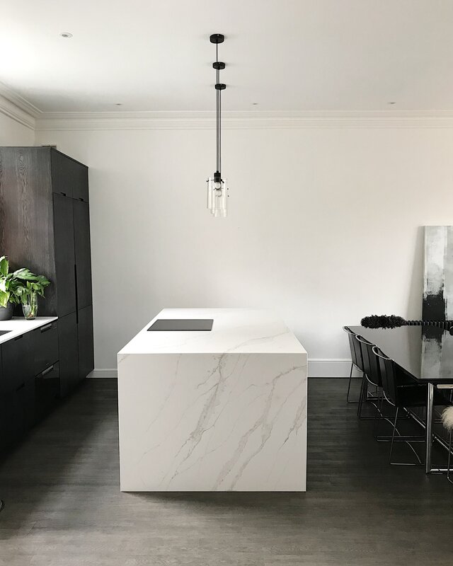 Sleek monochrome kitchen with marble countertop with a waterfall edge