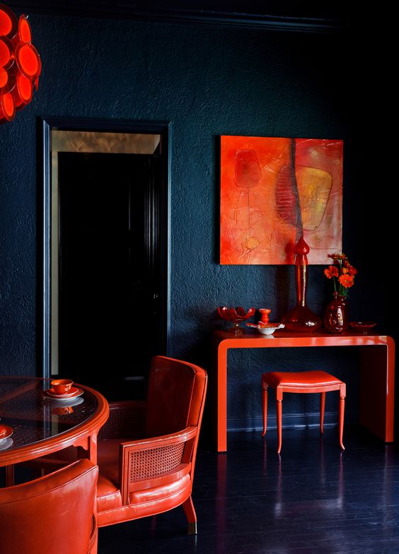Dark blue dining room with bold red accessories