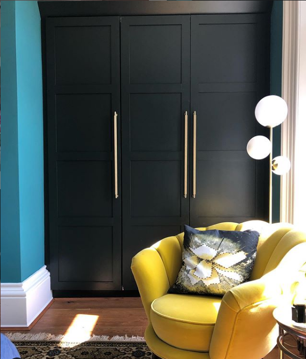 dark wardrobes with teal walls and gold accessories. Yellow flower velvet armchair