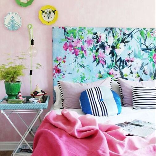 Dark blue living room with a large metal wall hanging and a pink velvet sofa