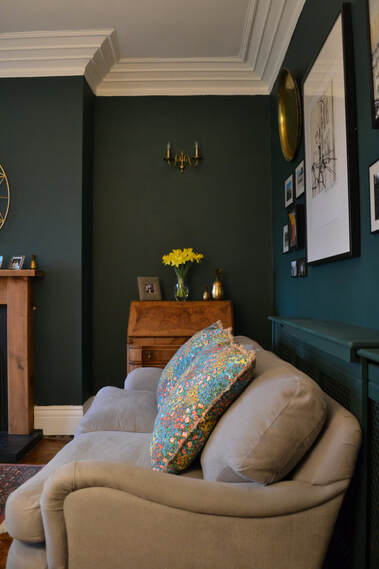 dark green living room with grey sofa and wood accents