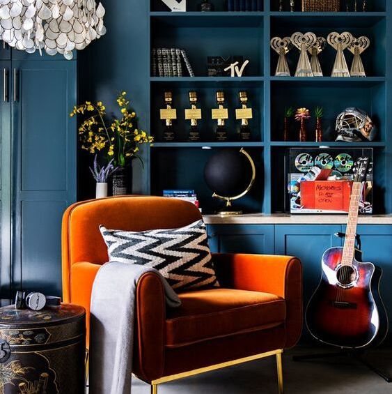 orange arm chair in front of dark blue shelving