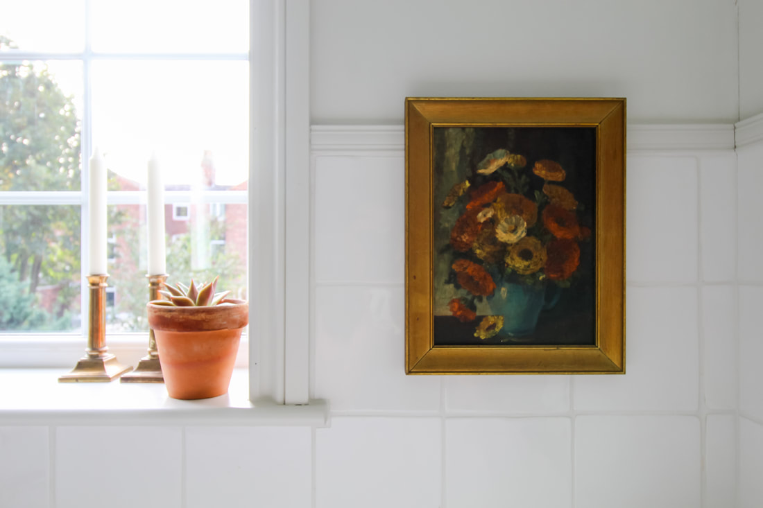floral oil paintings with candle sticks and terracotta potted succulent on the window sil