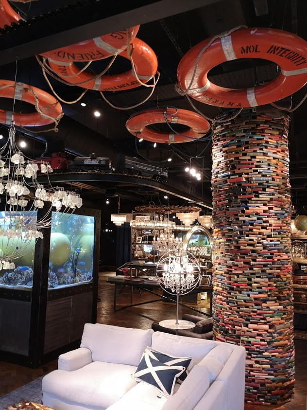 inside timothy oulton,  collumns are clad in books and the ceiling hosts suspended flotation devices