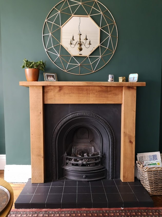 dark green living room with white architectural details and a a medium wood tone fireplace surround