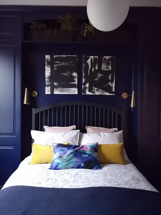 dark blue panelled bedroom with art and greenery