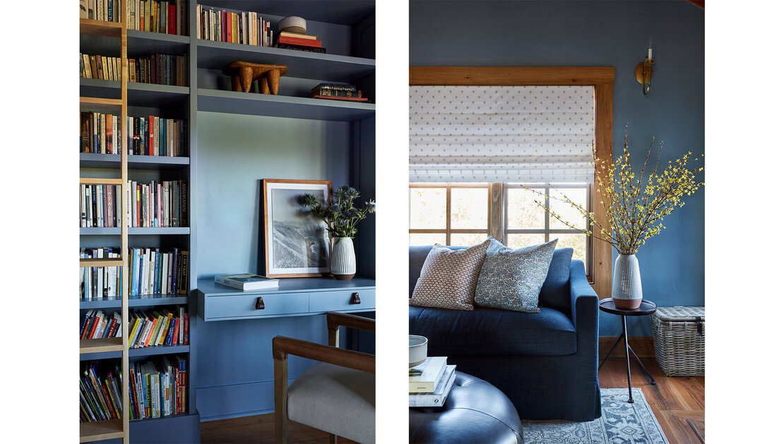 Dark study with a blue sofa and blue cabinetry with a library ladder