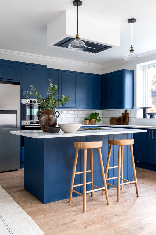 blue and white kitchen with island and stainless steel appliances. styled with antiques, art and wood tones