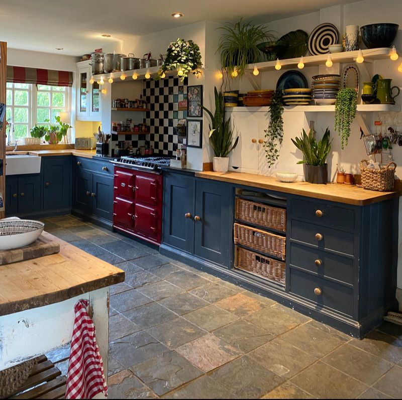 Dark blue country kitchen with slate flooring and a red aga stove