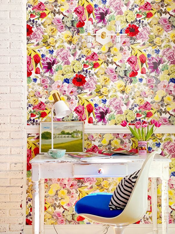 yellow red and pink floral wallpaper with a white writing desk in front 