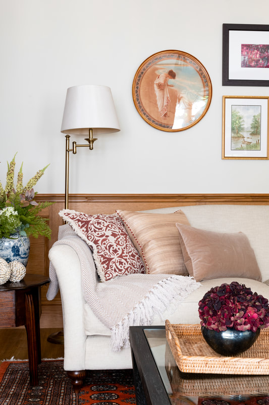 layered cushions on a sofa in a living room with pink tones and wood panelling