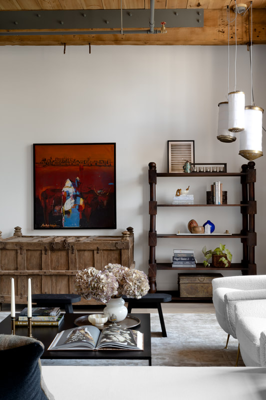 living room with an eclectic design using rustic style antiques and lighting. Morroccan lanterns on the right with a Sudanese painting in deep red and orange colours.