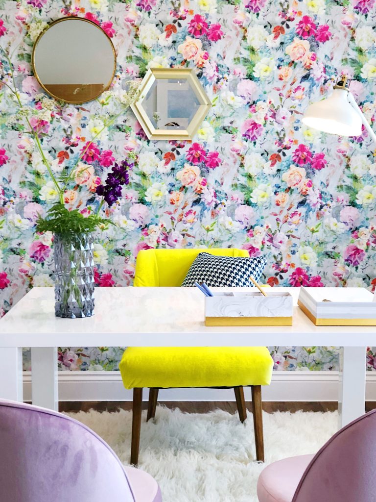 yellow chair in front of bold floral wallpaper with purple chairs
