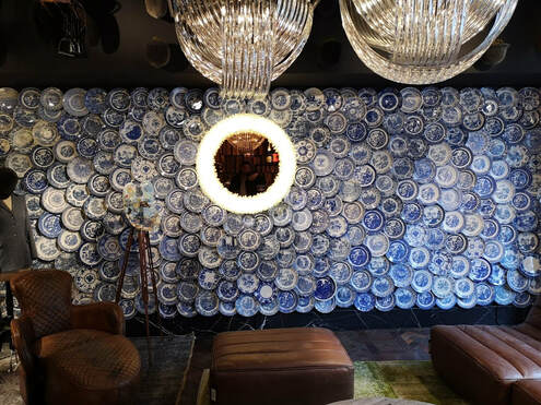 inside timothy oulton where a whole wall is covered in blue and white chinoirsery plates. 