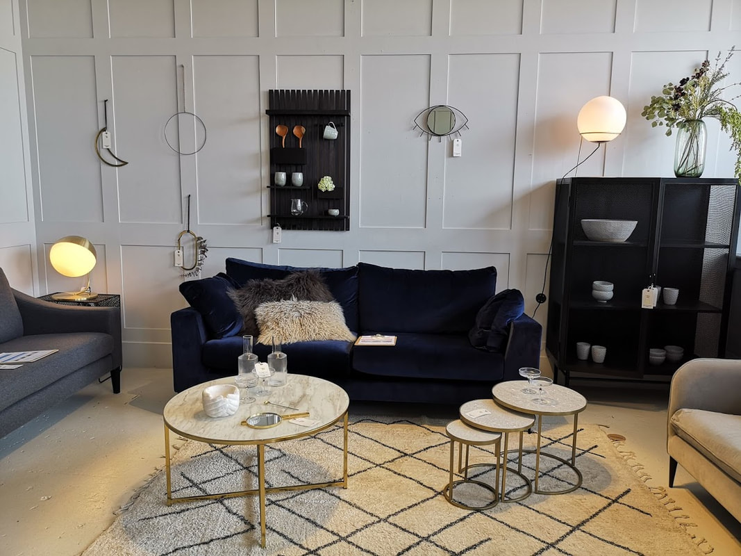 rose and grey showroom with a blue velvet sofa and mid century tables.