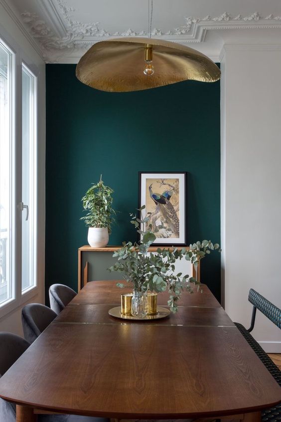 large brass pendant against a green backdrop