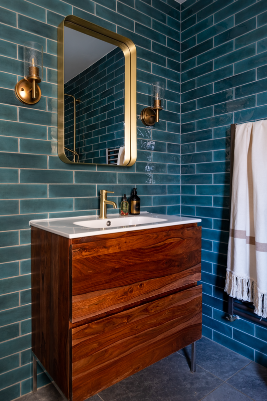 teal bathroom with a wood vanity with gold accesories