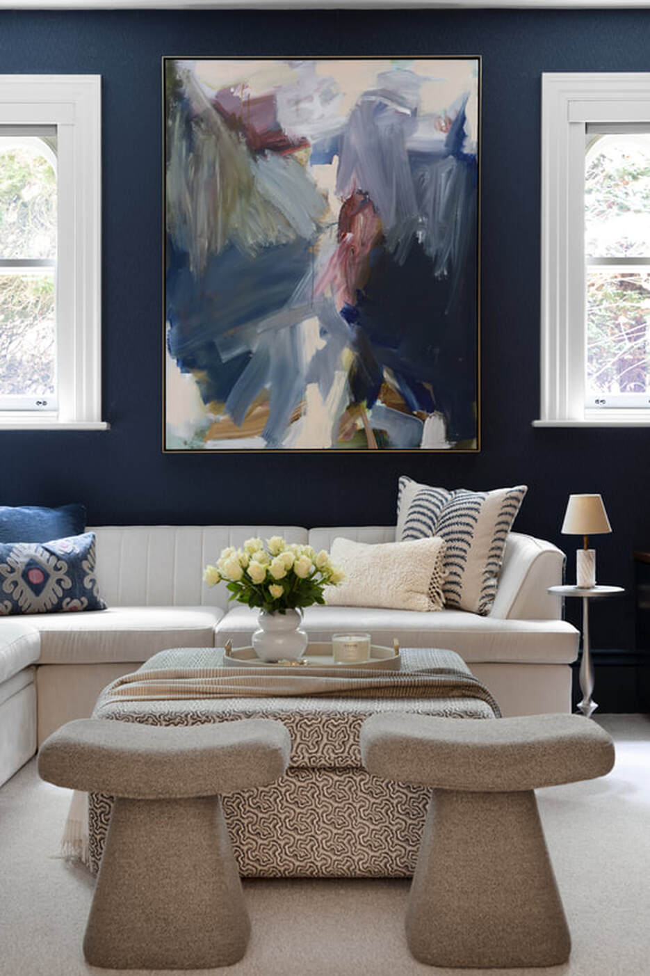 inky blue living room with textured wallpaper and white sofas and colourful art. 